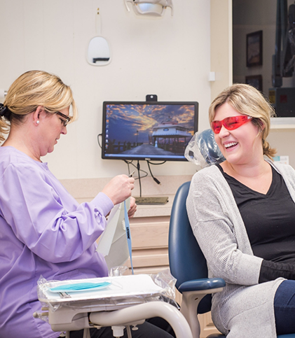 Female dental team member speaking to female patient in treatment chair