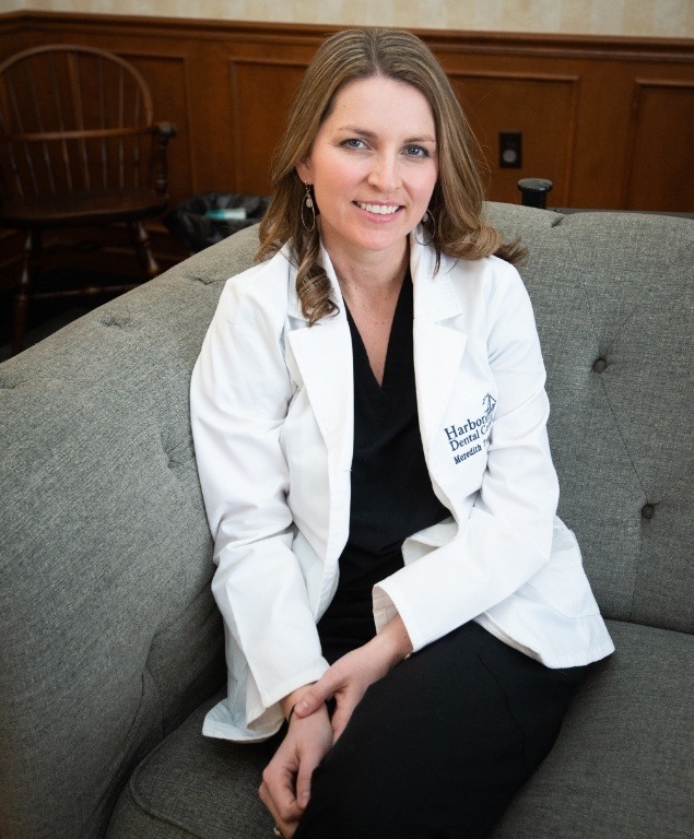 Doctor Meredith Todd in white lab coat sitting on couch