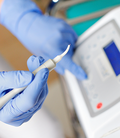 Gloved hands holding a dental laser