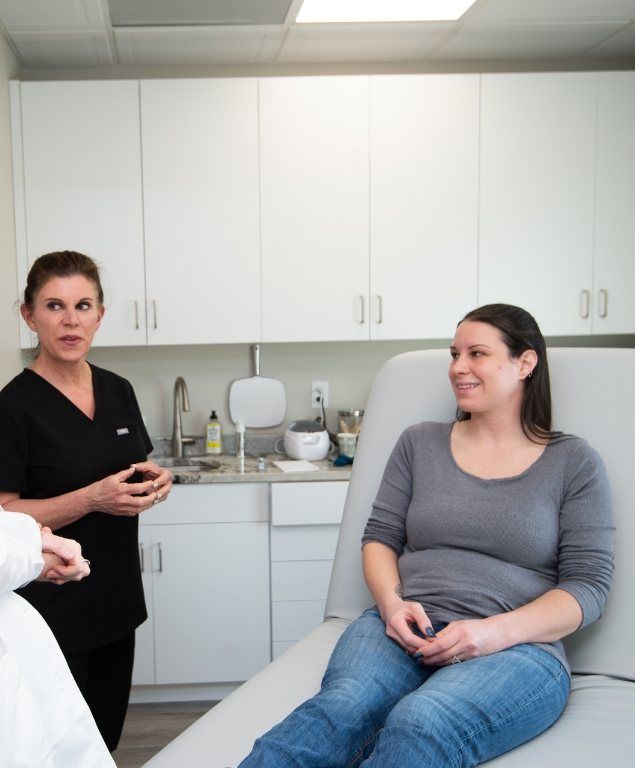Woman sitting in dental chair talking to two dental team members