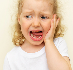 Little girl rubbing her jaw in pain