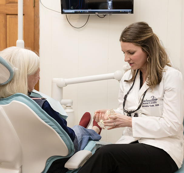 Dentist showing model of teeth to older female patient