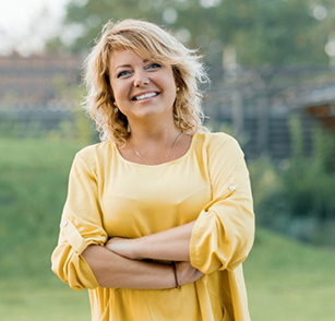 Woman in yellow shirt smiling with arms folded