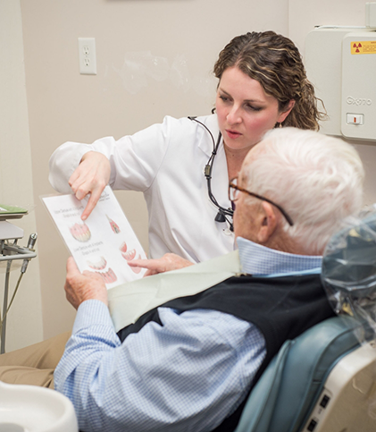 Dentist showing pamphlet to man in dental chair