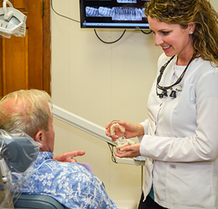 Dentist speaking to male patient in chair