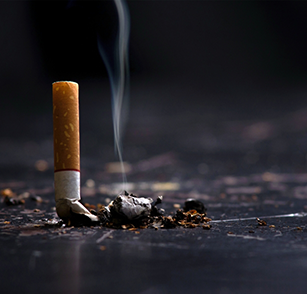 Extinguished cigarette smushed against black surface