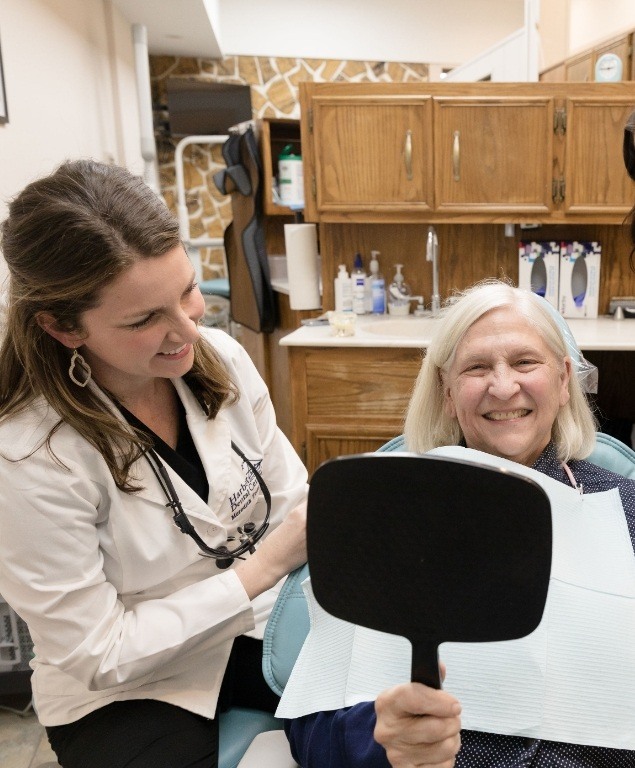 Senior dental patient admiring her new smile in mirror