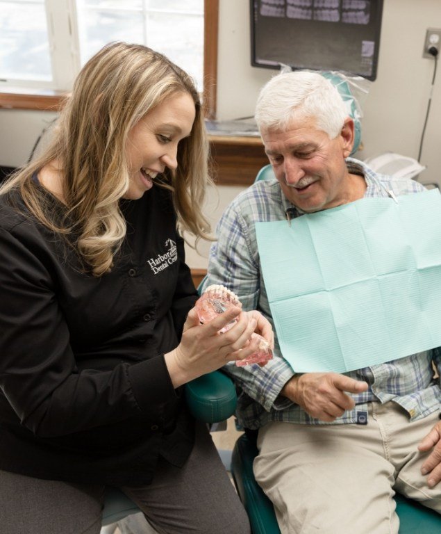 Dental team member showing a set of dentures to a patient