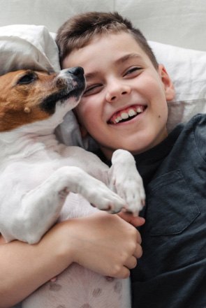Smiling young boy laying in bed with a cute dog