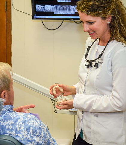 Dental team member smiling down at patient in chair