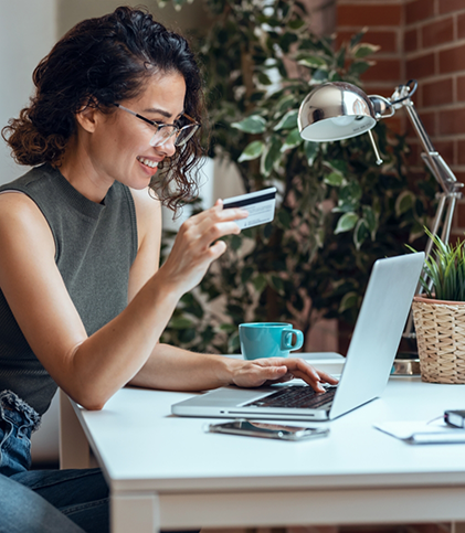Woman holding credit card and typing on laptop