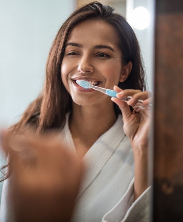 Young woman smiling while brushing her teeth