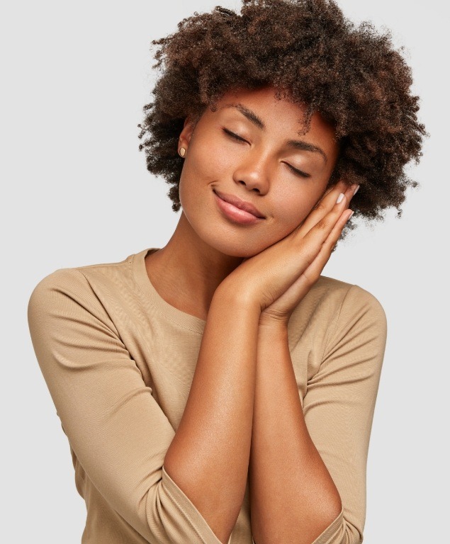 Woman making pillow shape with her hands and pretending to sleep