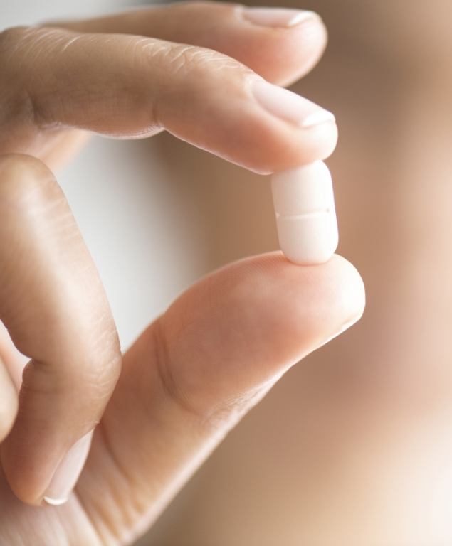 Close up of a hand holding a white pill