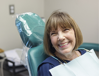 Woman with short hair sitting in dental chair and smiling