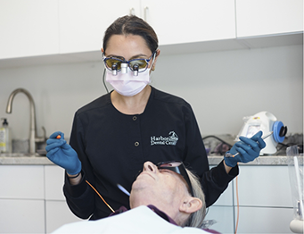 Female team member with mask treating a patient