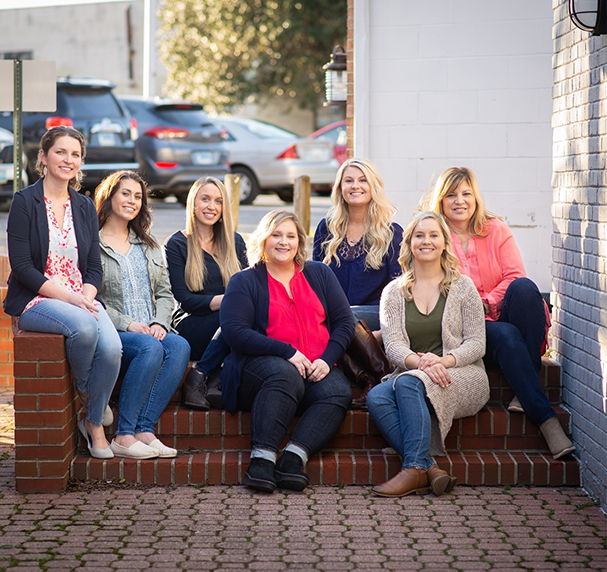 Multiple dental team members gathered on steps outside