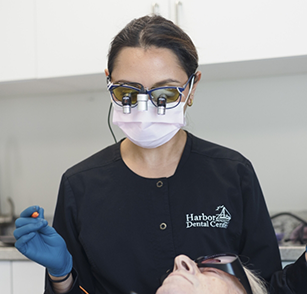 Team member with face mask and magnification glasses treating patient