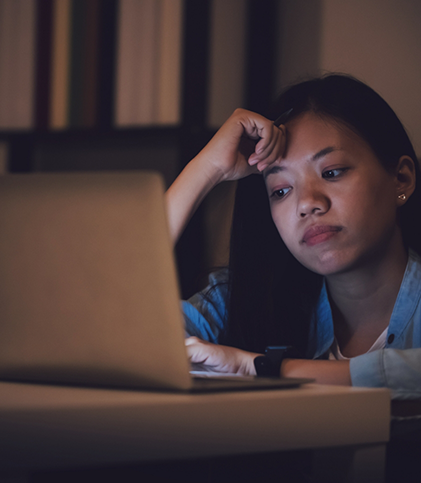 Woman typing on laptop at night and looking tired