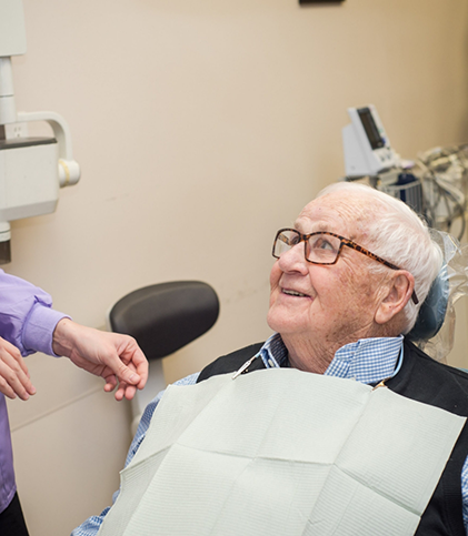 Older man with white hair and glasses sitting in dental chair