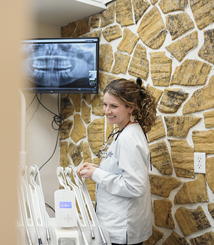 Dentist standing next to monitor displaying dental X ray