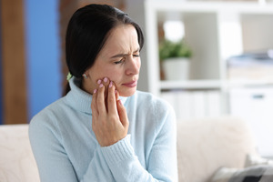 Woman with toothache rubbing her jaw